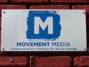 Sign that reads M Movement Media Communications Strategy for Social Change