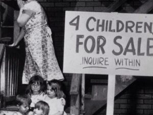 Black and white photograph that shows for children sitting on steps and a woman satnding behind them. A sign the righht reads "4 Children for Sale Inquire Within"
